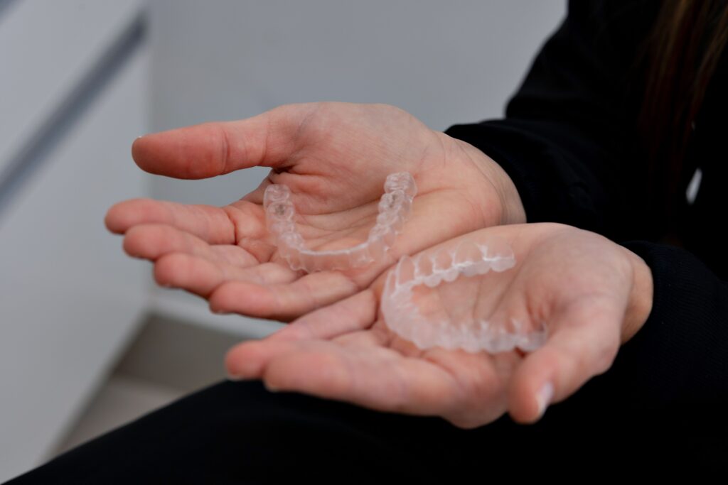 Clear dental aligners held in a dental office for adult Invisalign treatment